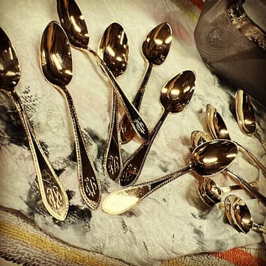 A set of high-karat antique spoons laid out on the bench.